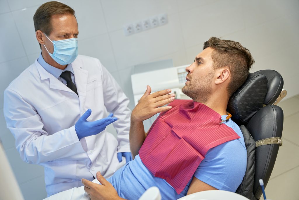 Dental specialist explaining something to his male patient