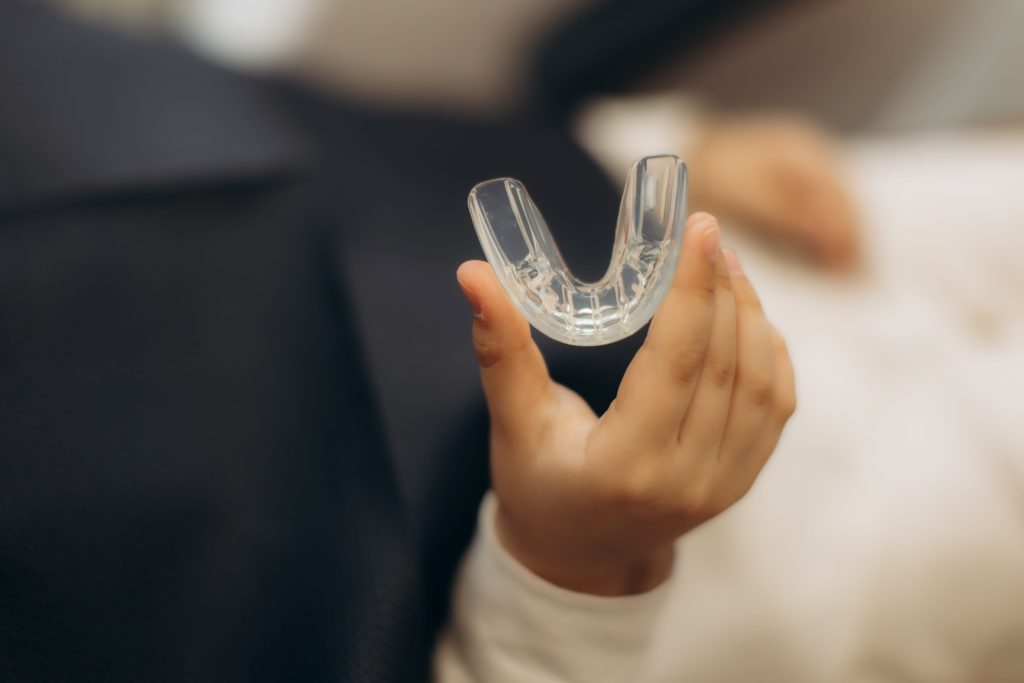 child holding clear dental retainer indoors